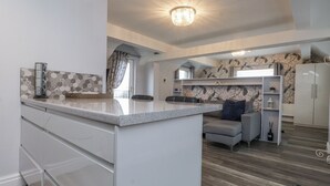 Cozinha moderna com ilha central, armários brancos e luminária pendente.