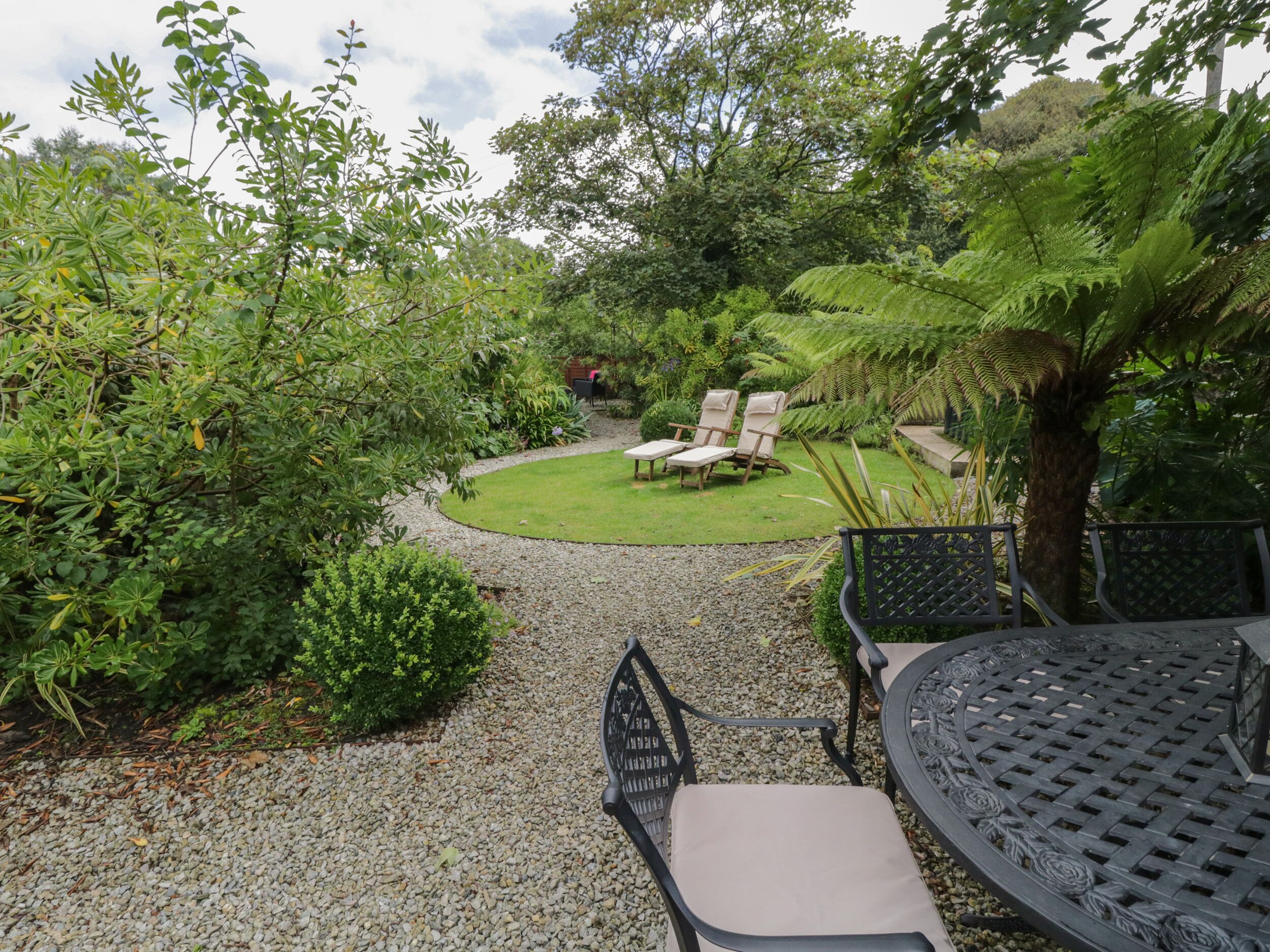 A garden with a gravel path, a lawn, and outdoor seating.