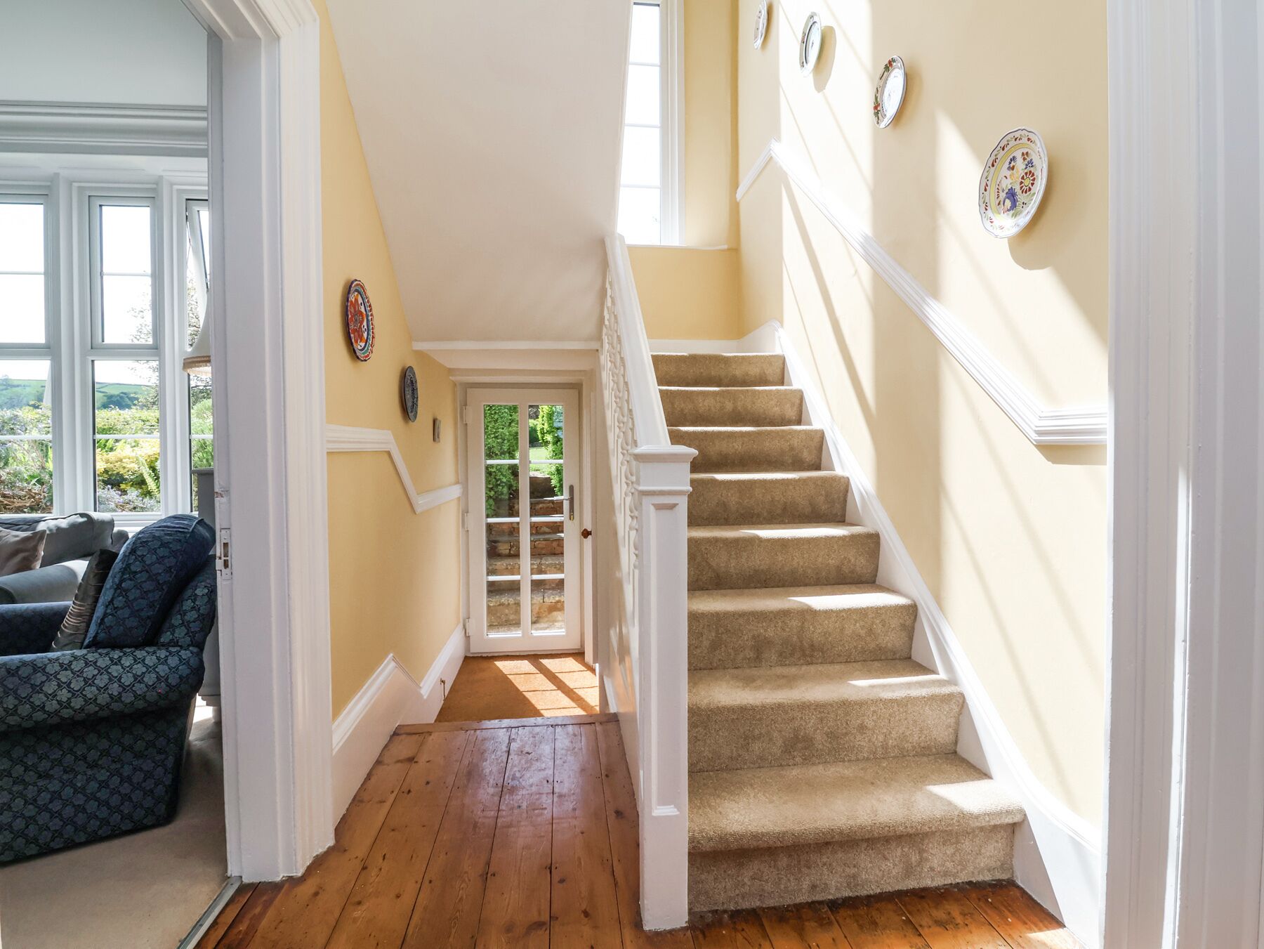 A staircase with beige carpet and white railings leading to a door with glass panels.