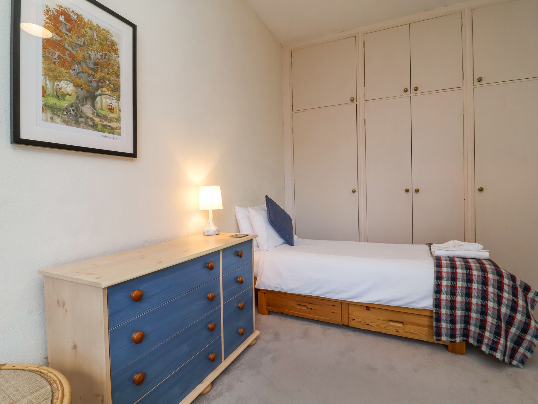 Un dormitorio con cama, cómoda, lámpara y armario.