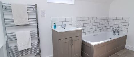 A modern bathroom with a skylight, a towel rack, a sink, and a bathtub.
