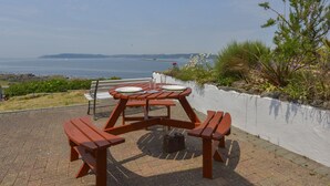 Mesa de piquenique com vista para o mar e terra ao longe.