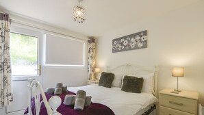 Quarto com cama, mesa de cabeceira, luminária, janela com cortinas e um quadro na parede.