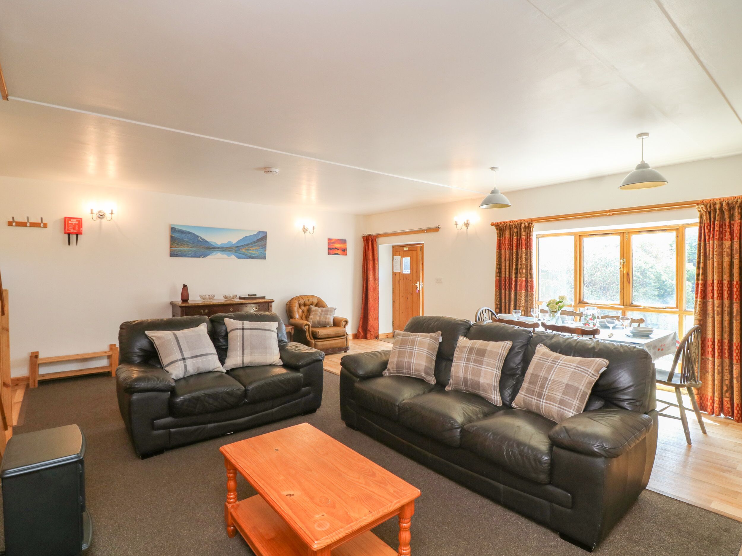 A living room with two black leather sofas, a wooden coffee table, and a dining area with a table set for four.