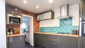 Eine moderne Küche mit grauen Schränken, einer Ziegelfassade, einer Mikrowelle, einem Gasherd und einem Toaster.