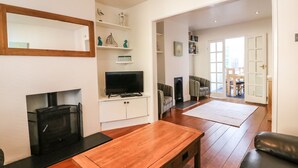 Ein Wohnzimmer mit Kamin, Fernseher und Couchtisch aus Holz.