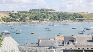 A harbor with numerous boats, buildings with traditional architecture, and a hilly landscape in the background.