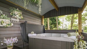 Un jacuzzi con un banco de madera y una mesa con un florero.