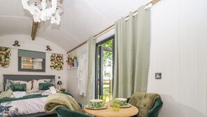 Un dormitorio con cama, mesita de noche, ventana con cortinas y vistas al exterior.