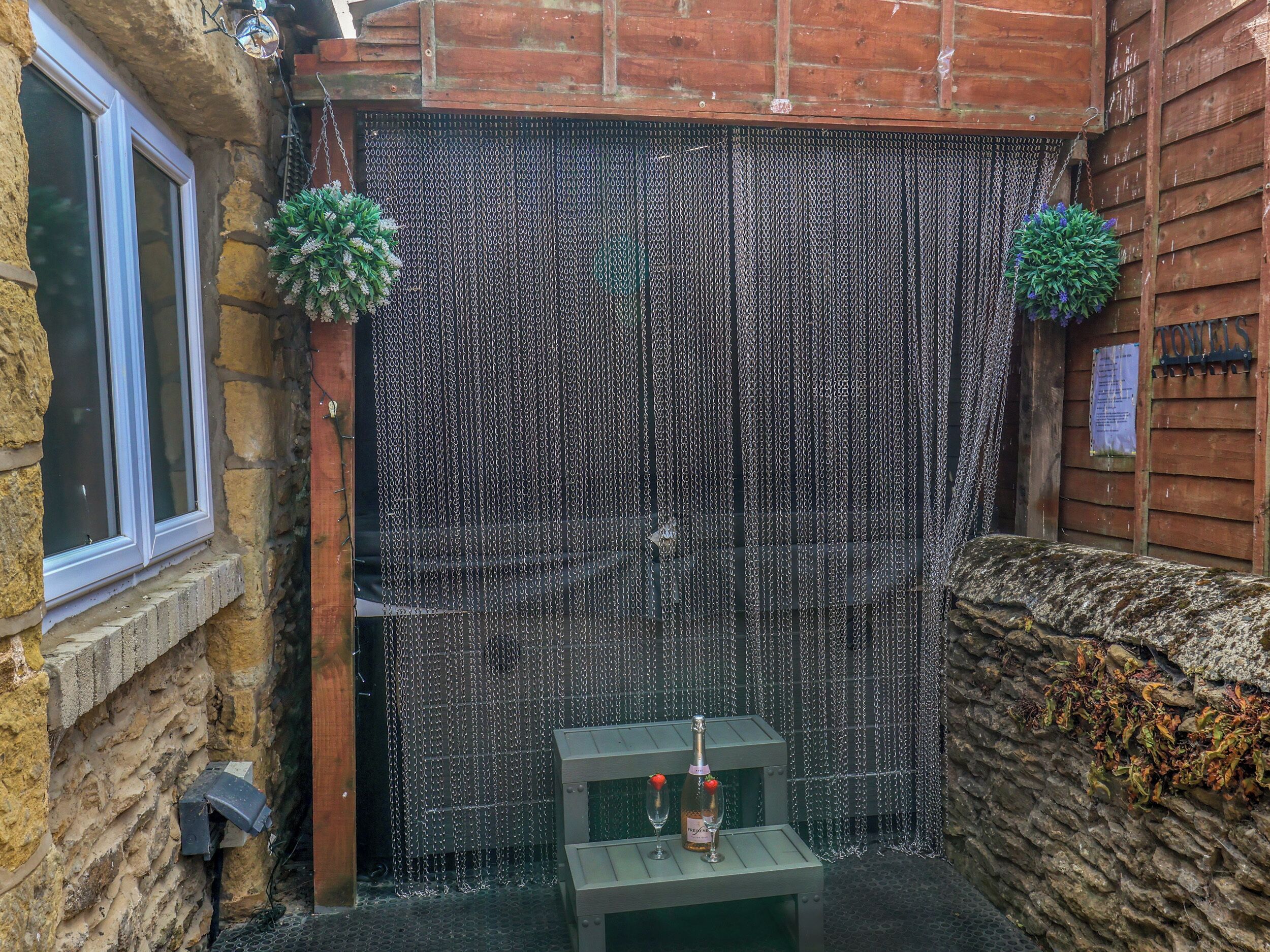 A stone wall with a chain-link fence, a small table with a bottle and glass, and a sign that reads 'TOWELS'.