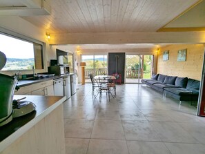 A spacious living area with a kitchen, dining table, and a sofa. - Charming 3-bedroom chalet with terrace near Alsace (Fraize)