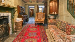 A room with a patterned carpet, a fireplace, a sofa, a chair, and a chandelier. - The Precinct House (Newton Stewart)