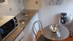 Una cocina compacta con un lavamanos de acero inoxidable, un microondas y una cafetera.