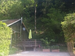 A cabin with a deck, surrounded by dense forest.