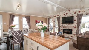 A modern kitchen with a wooden countertop, a built-in oven, and a dining area with a table set for four. - Jonstone Pines (Scarborough)