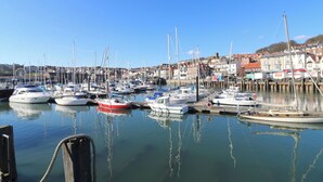 A marina with multiple boats docked, a clear sky, and buildings in the background. - Jonstone Pines (Scarborough)
