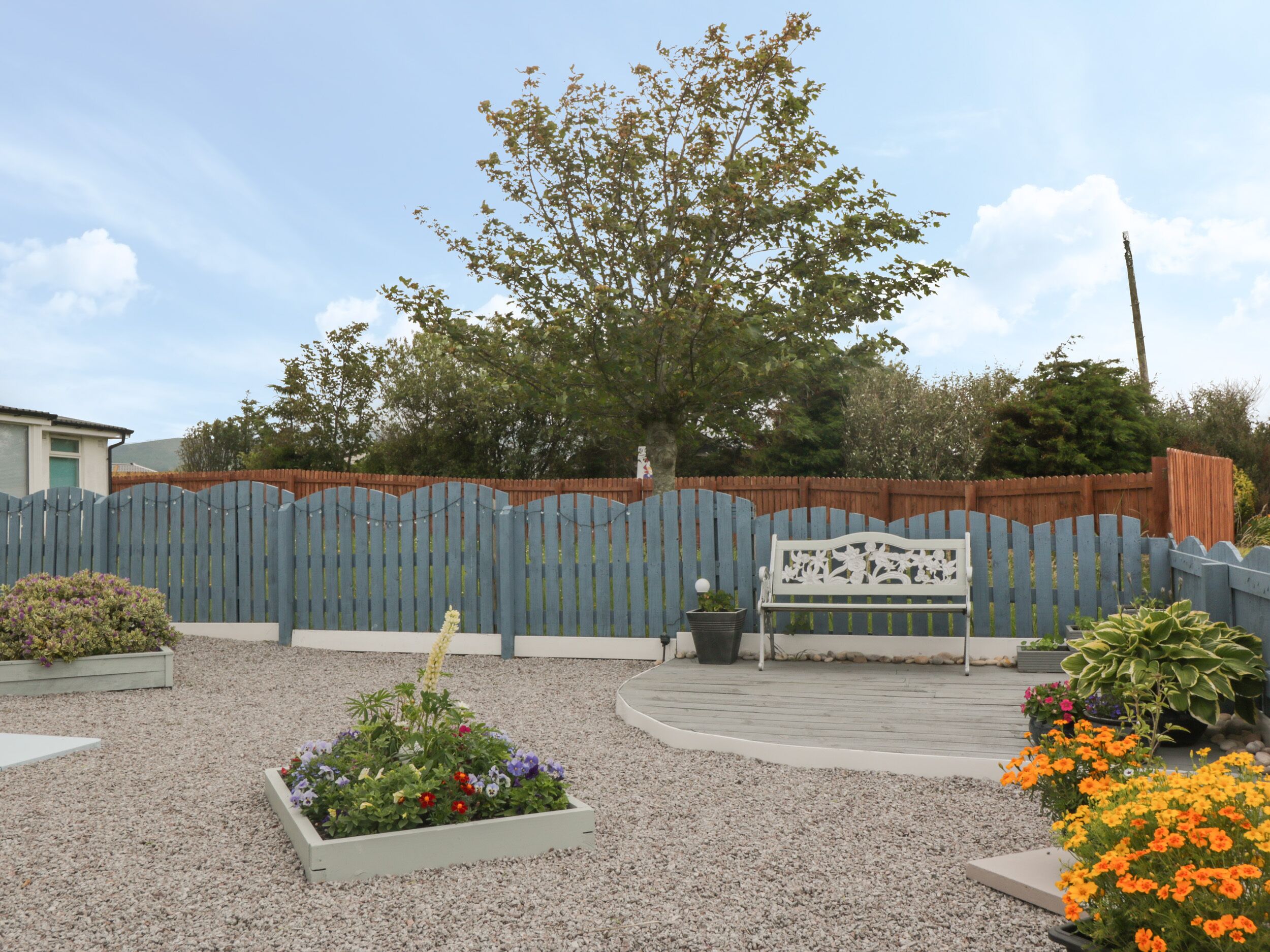 A garden area with a wooden fence, a bench, and various potted plants.