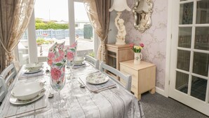 A dining area with a table set for four, a lamp, and a decorative mirror on the wall. - Sandpiper (Dumfries)