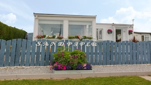 A modern house with a blue fence and the name "SANDPAPER" on it. - Sandpiper (Dumfries)