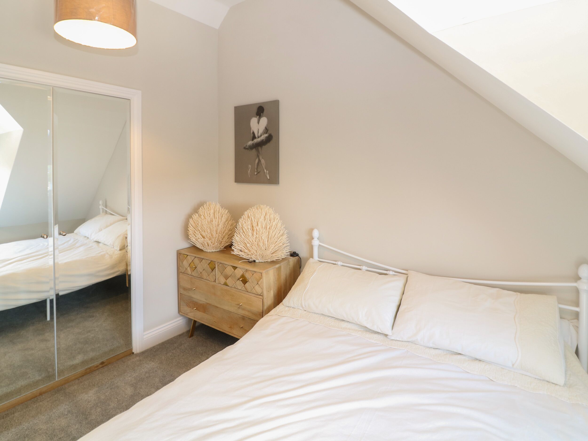A bedroom with a bed, a dresser, a mirror, and a painting on the wall.