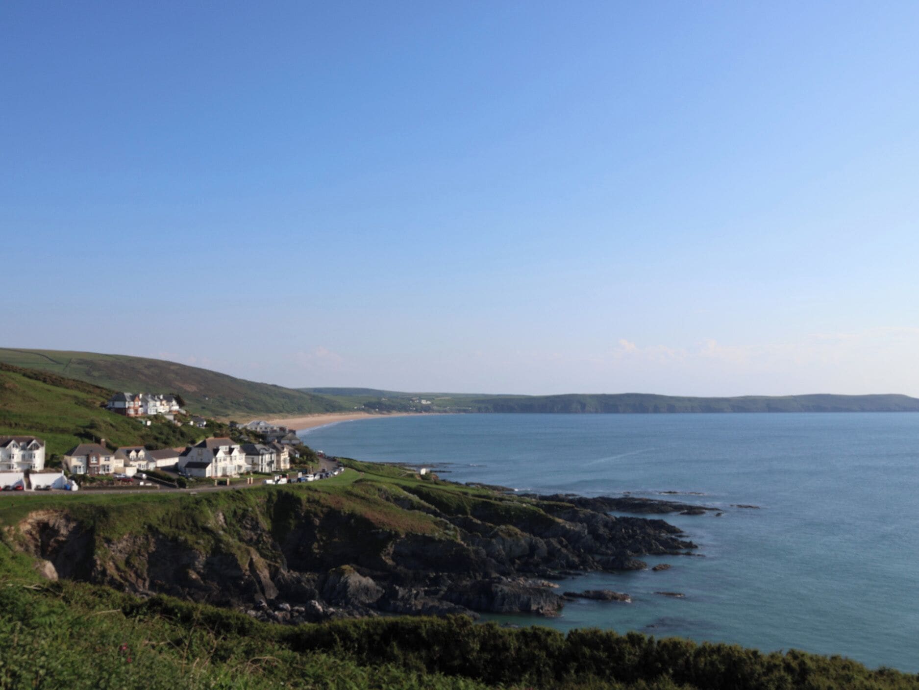 A coastal town with houses on a hillside overlooking the sea.