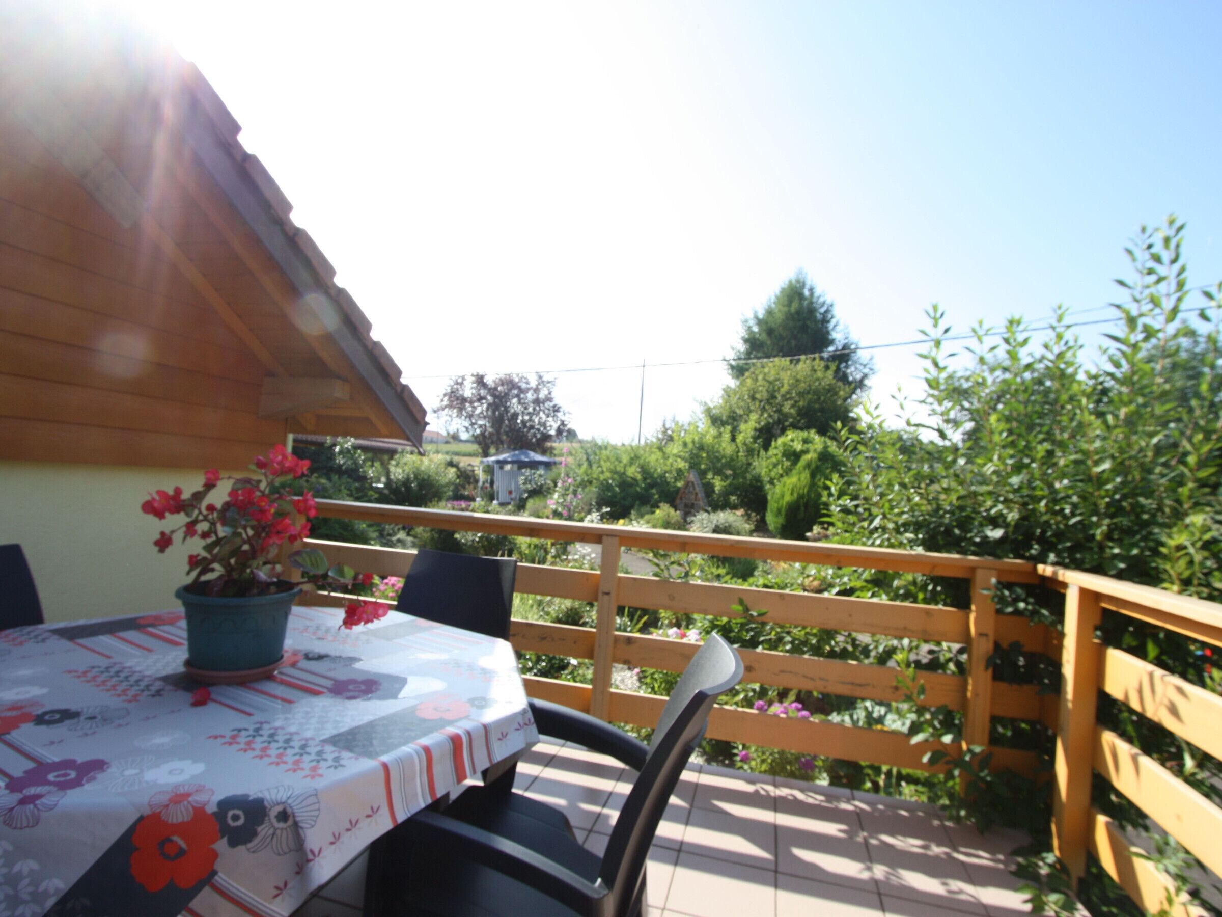 A patio with a table set for two, surrounded by a wooden fence and lush greenery.