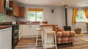 Una cocina moderna con armarios de madera, una isla central, horno empotrado y chimenea.