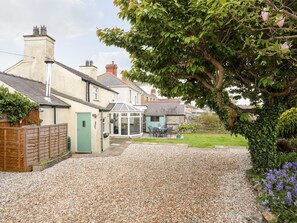 A residential area with houses, a gravel driveway, and a garden with flowers.