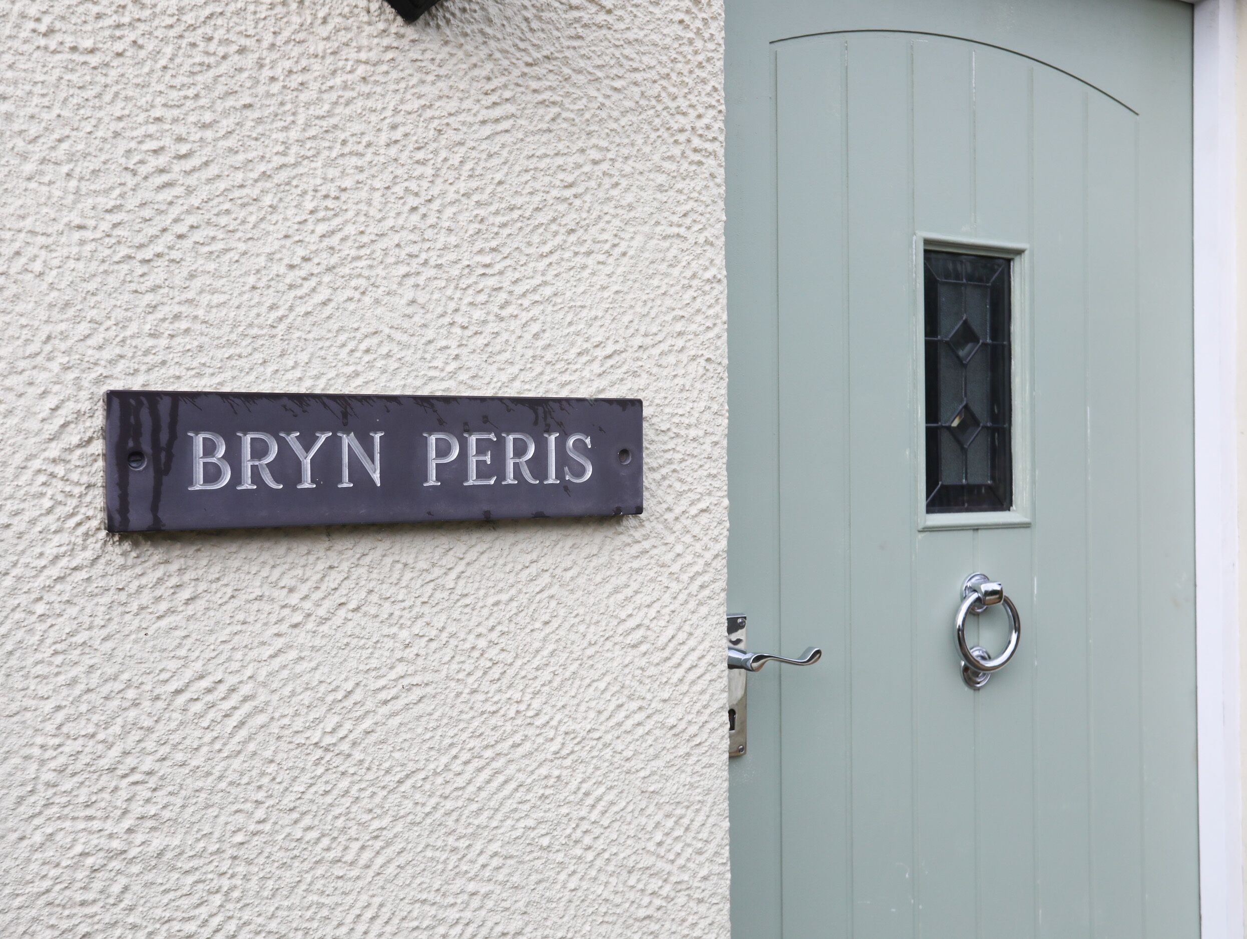 Una placa con el nombre 'BRYN PERIS' colocada en una pared con textura.