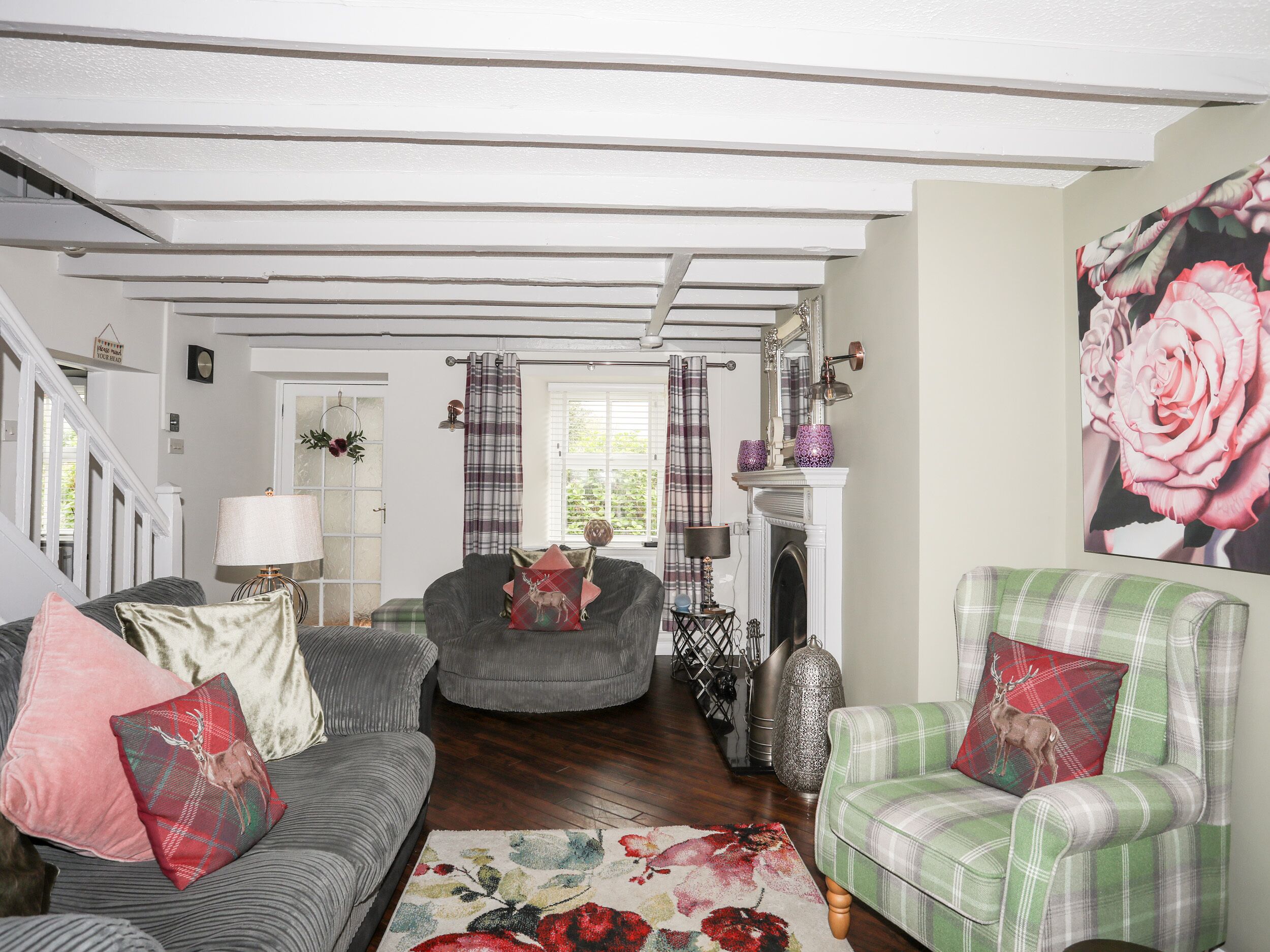 Ein gemütliches Wohnzimmer mit Kamin, Treppe und einem großen Blumenbild.