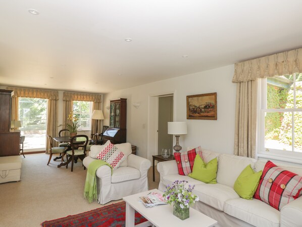 A living room with a white sofa, a dining table with chairs, a cabinet, and a painting on the wall.