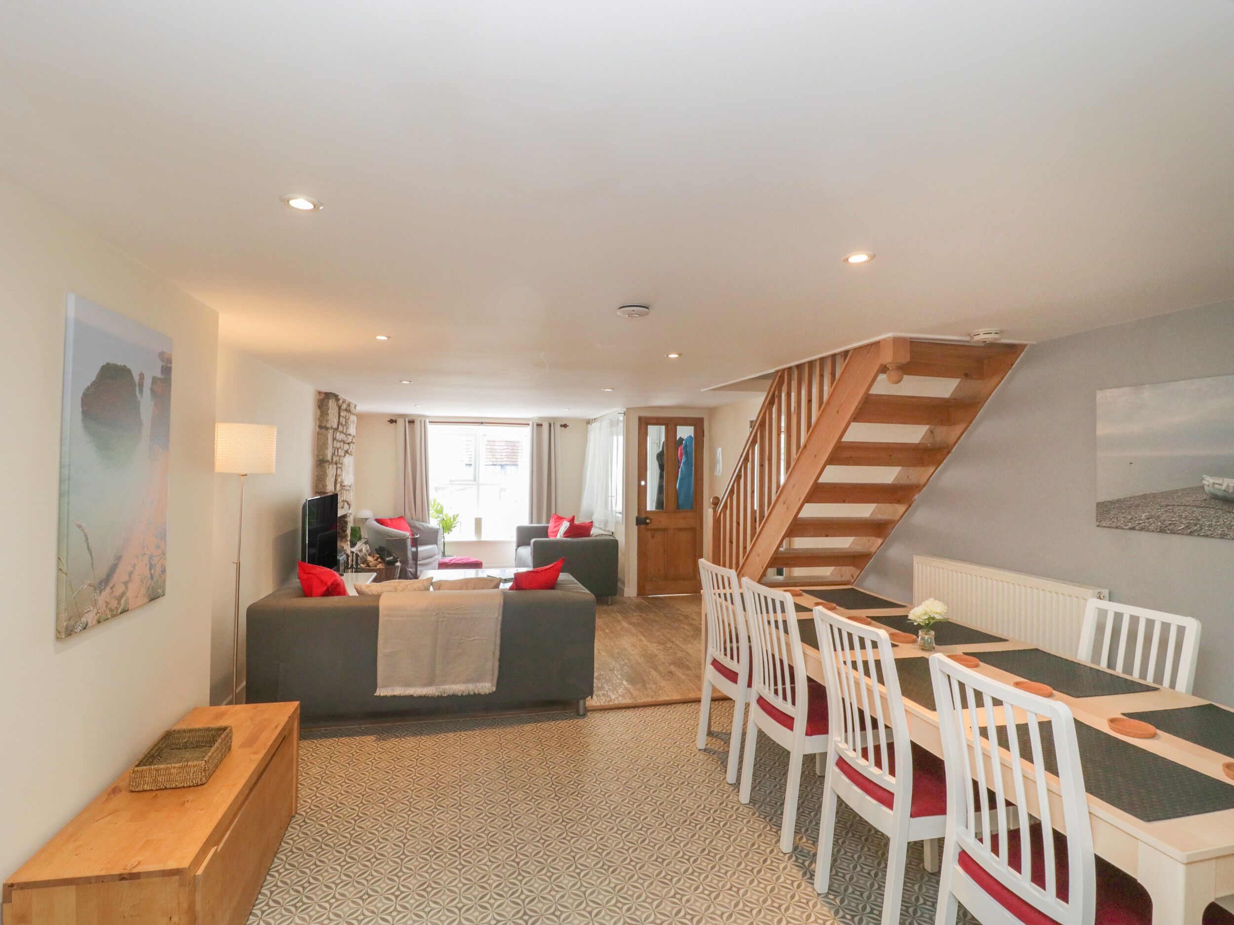 A spacious living area with a sofa, chairs, a dining table, and a staircase.