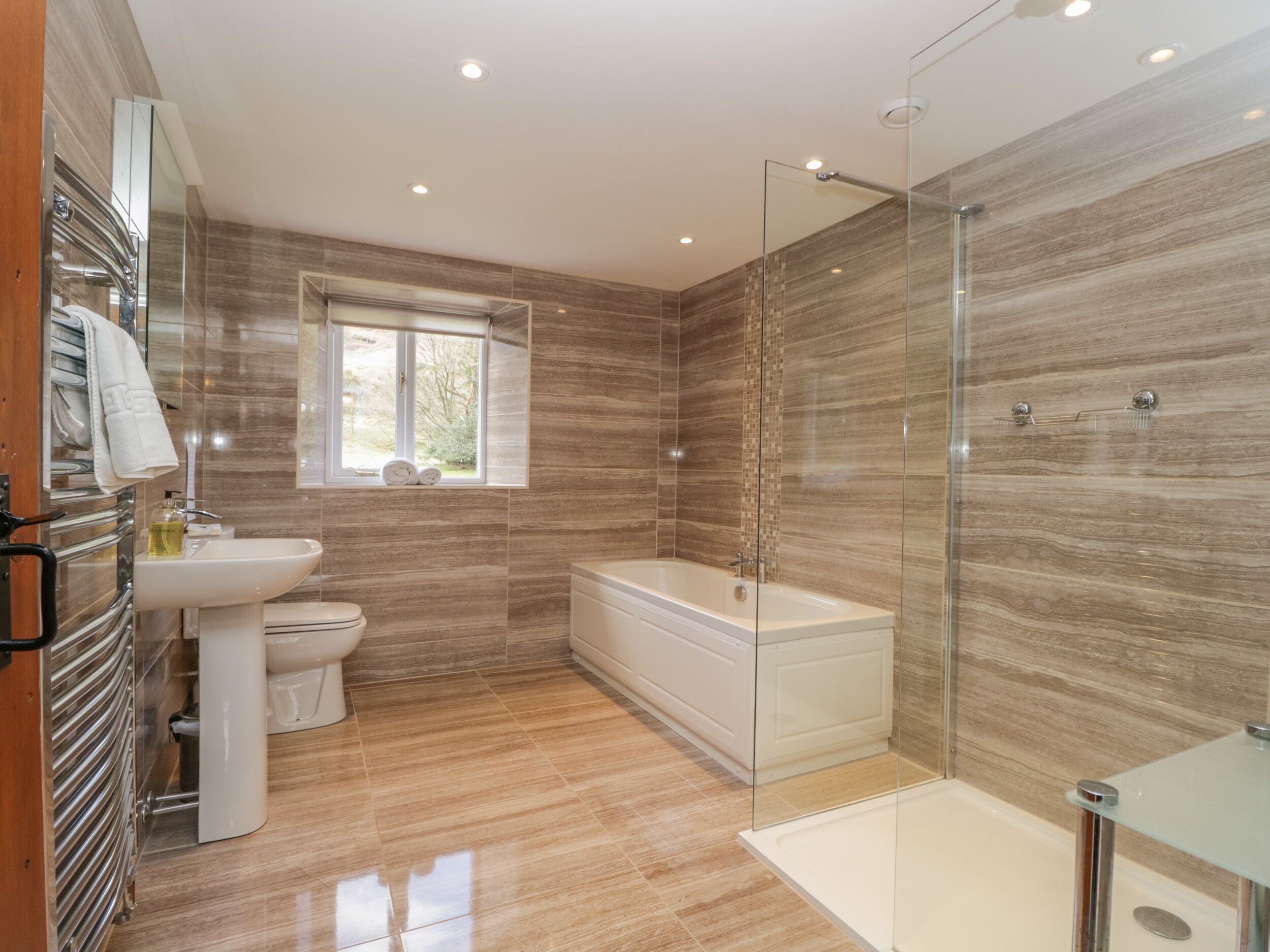Un bagno moderno con cabina doccia in vetro, una vasca da bagno freestanding, un water e un lavabo.