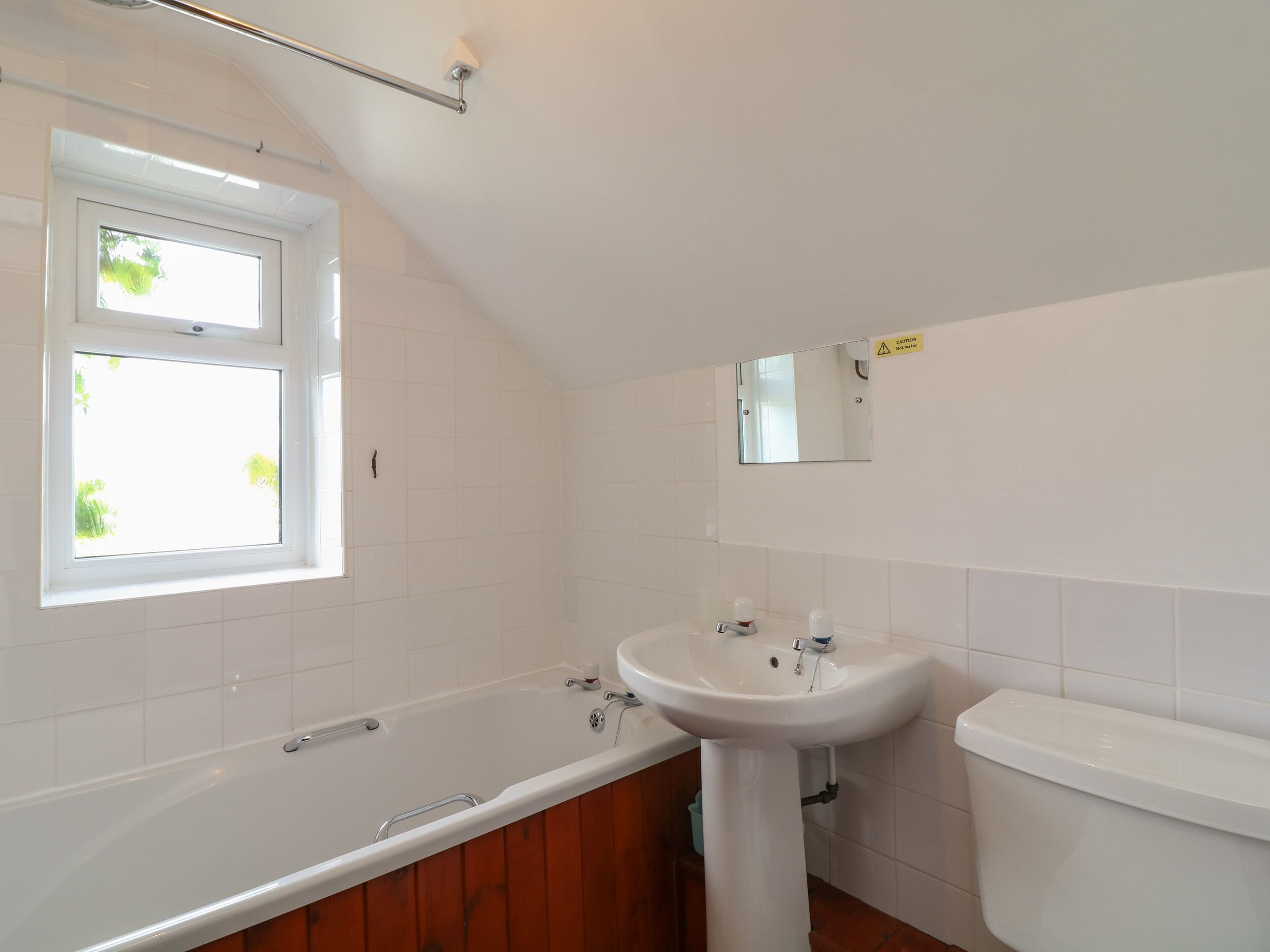 A bathroom with a bathtub, a sink, and a toilet. There is a window providing natural light.