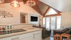 A modern kitchen with white cabinetry, a built-in oven, and a wooden countertop. There is a large window providing natural light and a view of the outdoors. - Treetops (Newcastle-upon-Tyne)