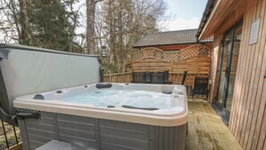 A hot tub on a wooden deck with a wooden fence and a building in the background. - Treetops (Newcastle-upon-Tyne)