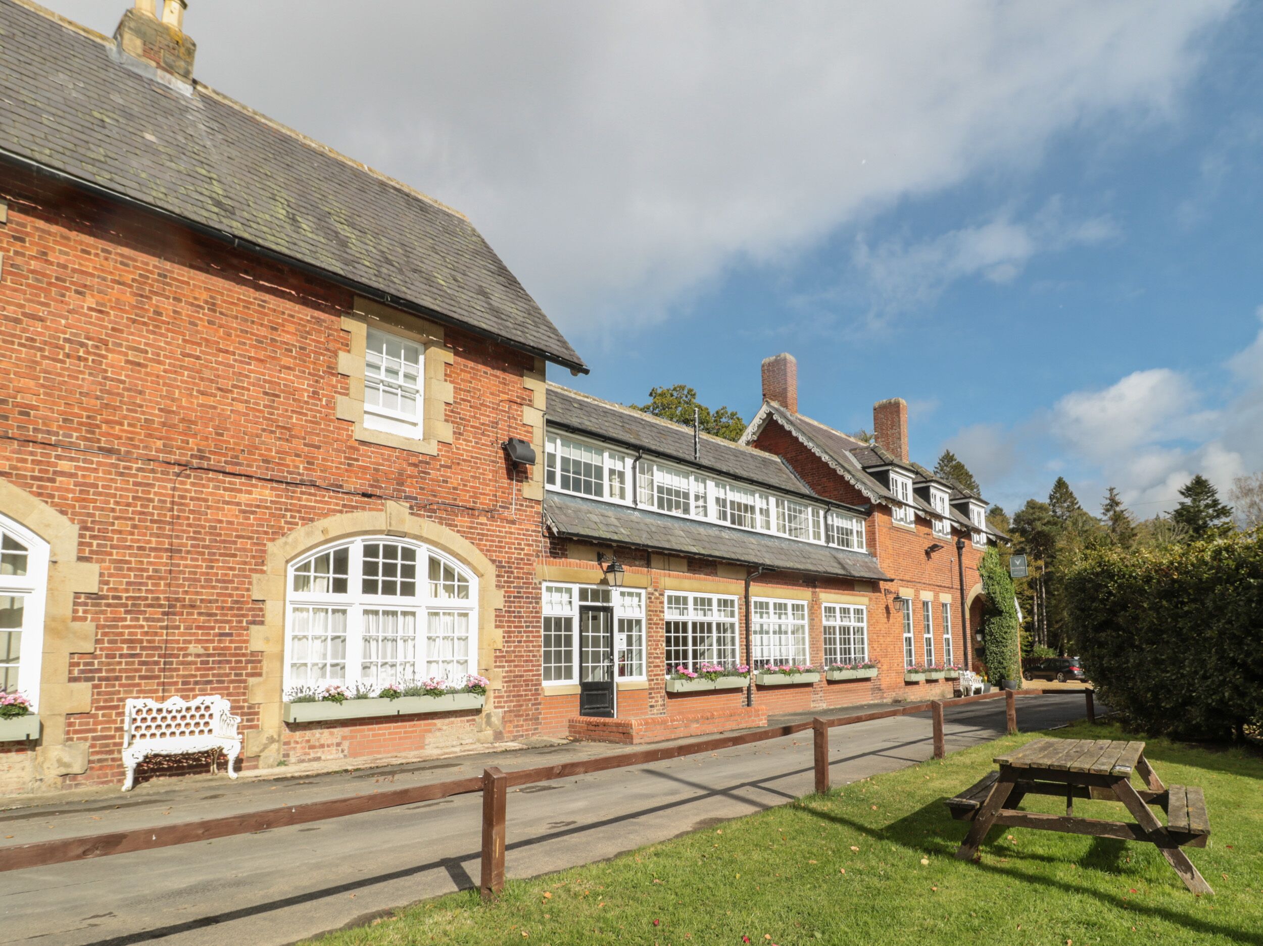 A traditional brick building with large windows and a bench outside.