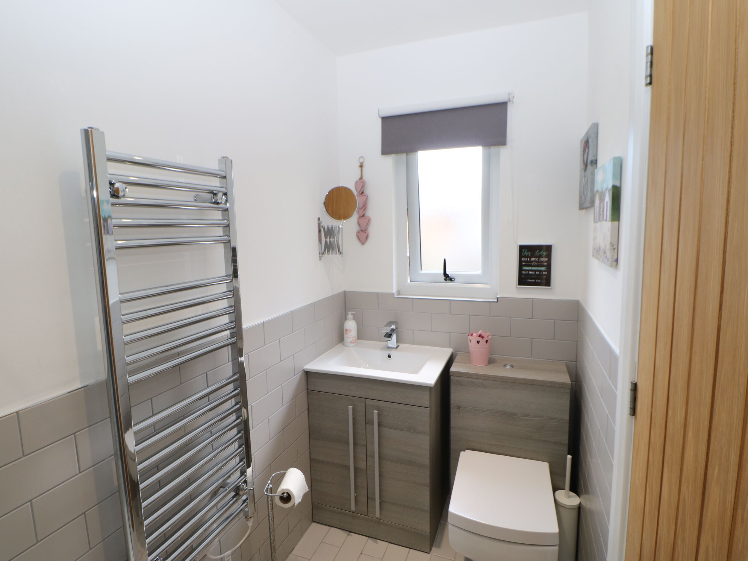 A bathroom with a chrome towel rack, a toilet, a sink, and a window with a view.