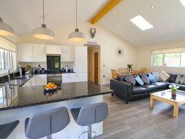 Una cocina moderna con una isla central, un área de comedor con un sofá y una sala de estar con una mesa de centro.