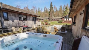 A hot tub with a wooden deck, wooden buildings, and a fenced yard. - Barn Owl (Newcastle-upon-Tyne)