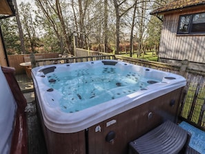 A hot tub with a wooden deck, a wooden fence, and a small wooden structure in the background. - Barn Owl (Newcastle-upon-Tyne)