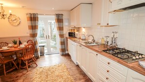 Una cocina con armarios de madera, una estufa y un comedor con mesa y sillas.