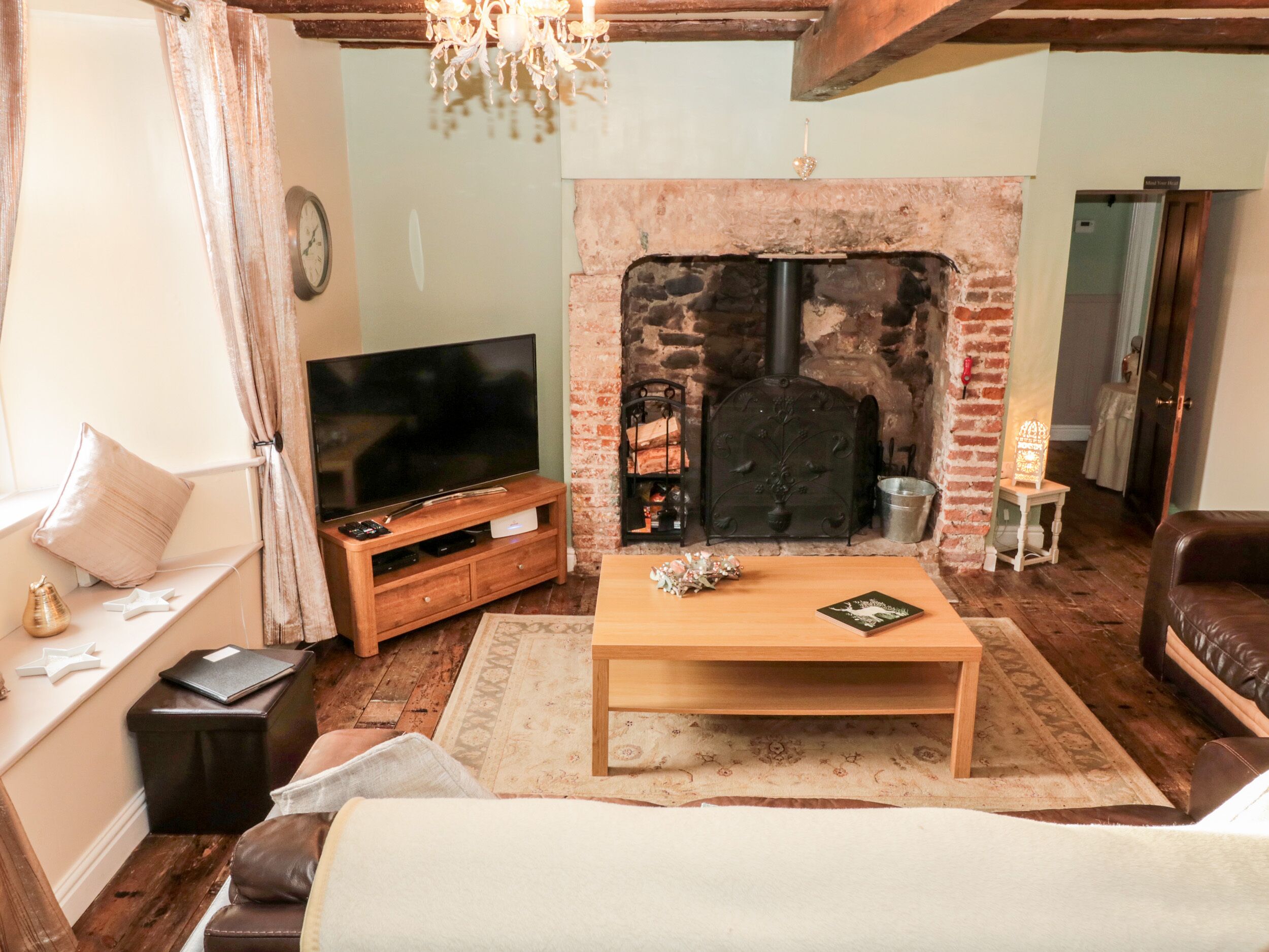 A cozy living room with a fireplace, wooden furniture, and a television.