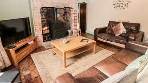 Un salón acogedor con chimenea, sofá de cuero, mesa de centro de madera y televisor de pantalla plana.