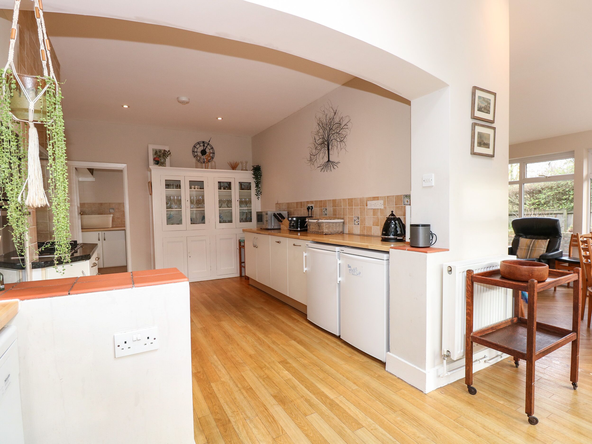A kitchen with white cabinets, a wooden countertop, and a dining area with a chair.