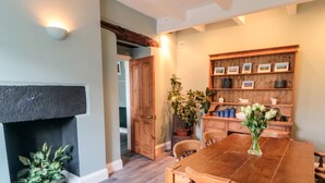 A dining area with a wooden table and chairs, a fireplace, and a wooden cabinet with framed pictures.