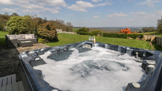 Un jacuzzi con vista a un paisaje campestre, que incluye una casa y vegetación.