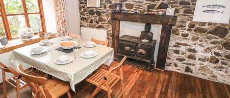 A dining area with a stone wall, a fireplace, and a table set for four.