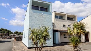 Un edificio de dos pisos con fachada azul claro y techo plano.