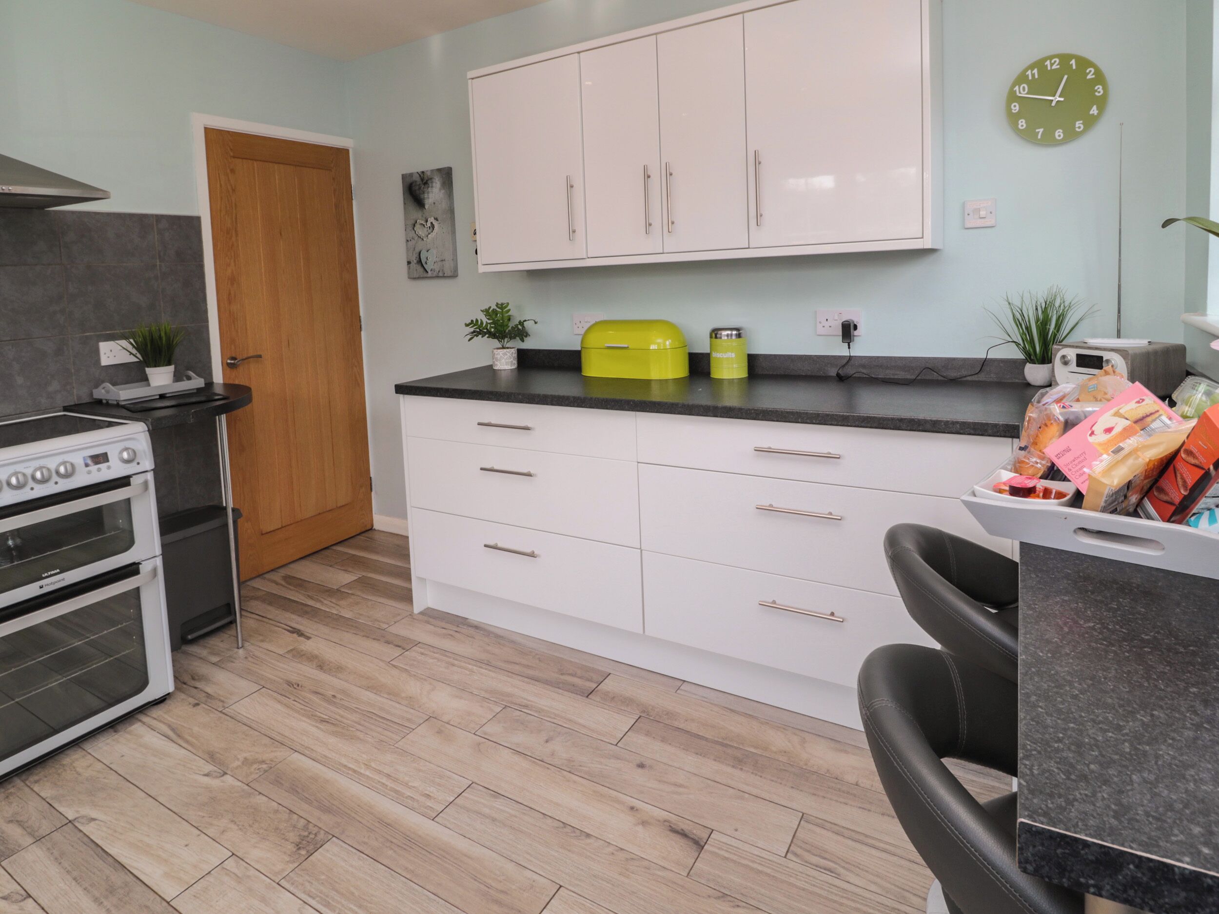 A modern kitchen with white cabinets, a black countertop, and a yellow appliance.